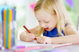 Cute little girl drawing with colorful pencils at a daycare. Creative kid painting at school. Girl doing homework at home.