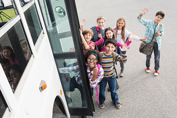 Group of multi-ethnic elementary school children (10-12 years) getting on school bus.